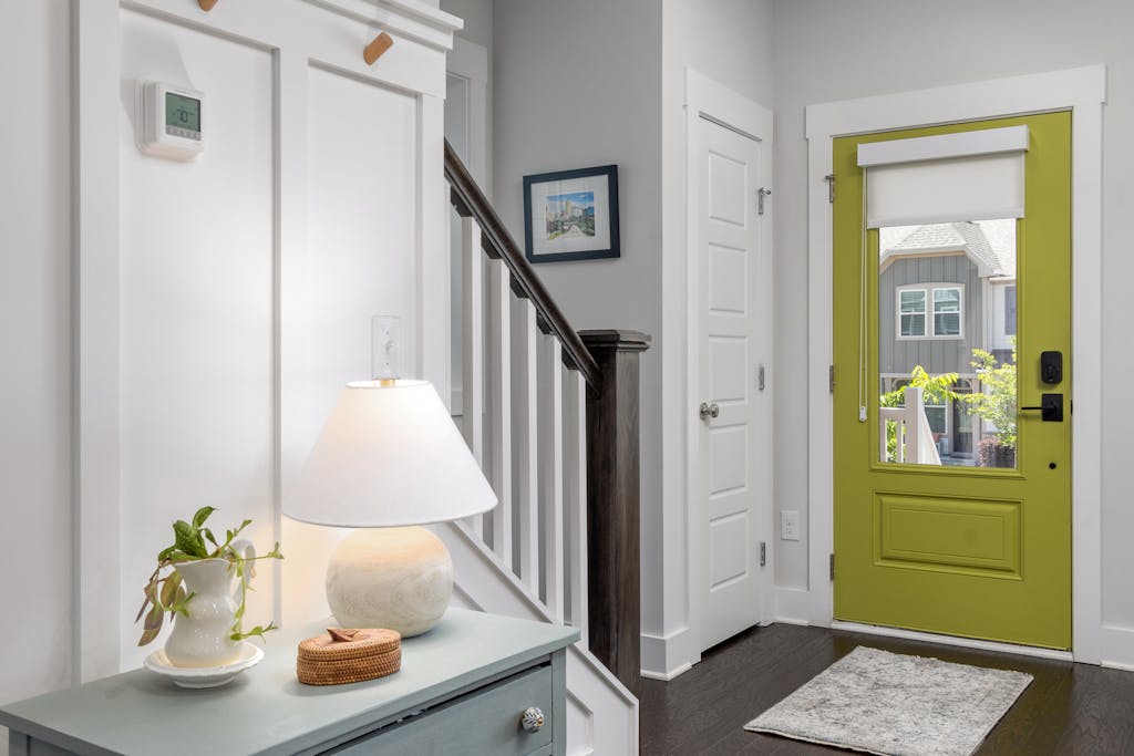 A well-lit modern entrance featuring a green door and stylish interior design elements.